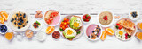 Fototapeta  - Healthy breakfast or brunch table scene on a white wood banner background. Overhead view. Avocado toast, smoothie bowls, oats, yogurt and a variety of nutritious foods.