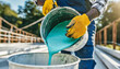 Closeup shot of a construction worker pouring out epoxy resin from a bucket onto a floor