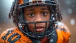  a close up of a young person wearing a football uniform and a helmet with snow falling all over the top of the helmet, and on the side of his face.