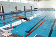 © Wavebreak Media - Caucasian female athlete swimmer dives into a swimming pool at an indoor facility
