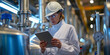 © T-elle - Engineer Analyzing Data on Tablet in Industrial Plant.A professional female engineer in a hard hat and safety glasses attentively reads a tablet amidst gleaming industrial equipment.