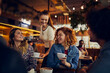 © Marko Geber - Waitress serving coffee to customers at a cozy cafe