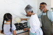 © Wavebreak Media - Biracial grandparents and granddaughter cooking pancakes in a modern kitchen