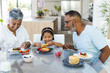 © Wavebreak Media - Biracial grandparents and granddaughter enjoy breakfast pancakes together at home