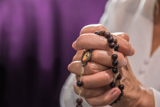 close-up detail of hands holding a rosary. mature woman praying.