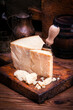 Traditionelles Parmesan Käse Stück mit Käse Messer bei der Speisezubereitung als close-up auf einem rustikalen Holz Schneidebrett 