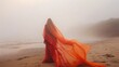 Unidentified figure wrapped in flowing coral cloth on a misty morning along the shore