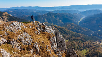 Wall Mural - Hiker man on edge of steep cliff on top of mountain peak Hohe Veitsch, Mürzsteg Alps, Styria, Austria. Idyllic hiking trail in alpine terrain. Wanderlust remote Austrian Alps in autumn. Rock formation