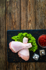 Wall Mural - Raw chicken drumsticks on cutting board with seasonings on wooden table
