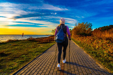 Nordic walking - beautiful woman exercising by the sea
