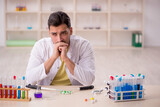 Fototapeta Sport - Young male chemist sitting at the lab