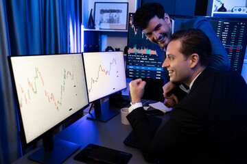 Cheerful two stock exchange traders raising fist up for digital currency achievement focusing on dynamic data background. Successful investors earning high profit analyzed by market graph. Sellable.