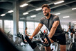 © EricMiguel - Smiling man enjoying a cycling workout at the gym, full of energy and motivation.