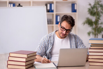 Wall Mural - Young male student preparing for exams in the classroom