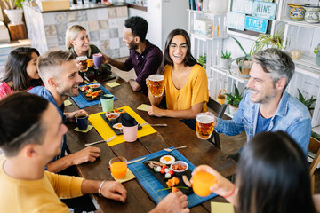 Wall Mural - Young group of friends having breakfast or brunch sitting at restaurant table. Food and drink concept.