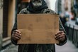 Homeless person holding up cardboard sign - vagabond panhandling on the street corner
