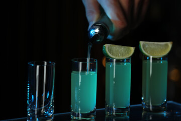 Poster - Bartender pouring alcohol drink into shot glass on dark background, closeup