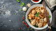 Indonesian Chicken Noodles. Chicken noodles in white bowl and wooden chopsticks on natural background with chicken pieces, chicken feet, green mustard, meatballs, boiled dumplings, sauce. 
