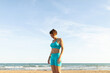 © StockRojoVerdeyAzul - A woman rests after performing Pilates exercises on the beach, facing the sea