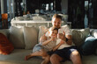 © Анастасія Стягайло - Father and son sit relax on couch in hotel hall have fun using cellphone together. Boy and dad makes selfie phone. Father and little boy child rest on sofa and watching funny video on smartphone.