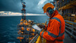 © apichat - An offshore oil rig worker in safety gear uses a tablet to check systems and processes, against the backdrop of the vast ocean and rig infrastructure.