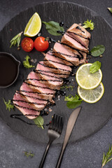 Wall Mural - sliced grilled cooked piece of tuna fillet on black stone serving board