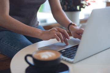 Canvas Print - Woman working on laptop computer in coffee shop, freelance at work, people lifestyle. Business woman in csual wear online working on laptop, surfing the internet at, cafe, remote work