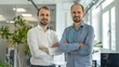 © Shani work - Two business partners in a bright office with a white background. They are both looking at the camera with hopeful smiles