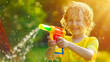 Young boy kid having fun with a water gun , summer activity with squirt pistol