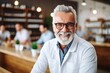 © Aleksandr - Smiling elderly white-haired pharmacist with a beard and glasses in a modern pharmacy
