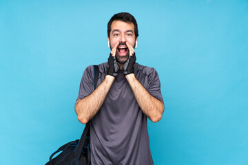 Wall Mural - Young sport man with beard over isolated blue background shouting and announcing something