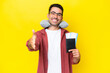 © luismolinero - Young handsome man with Inflatable Travel Pillow over isolated yellow background shaking hands for closing a good deal