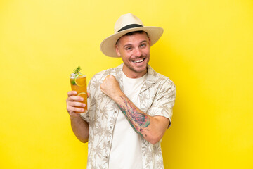 Wall Mural - Young caucasian man holding a cocktail isolated on yellow background celebrating a victory