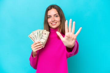 Poster - Young caucasian woman taking a lot of money isolated on blue background counting five with fingers