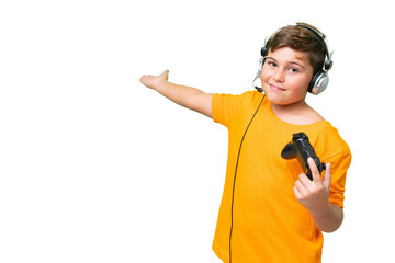 Little caucasian kid playing with a video game controller over isolated chroma key background extending hands to the side for inviting to come