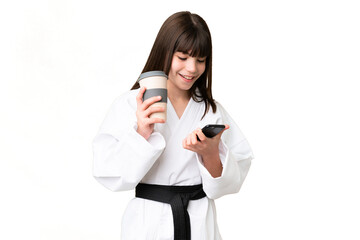 Sticker - Little Caucasian girl doing karate over isolated background holding coffee to take away and a mobile