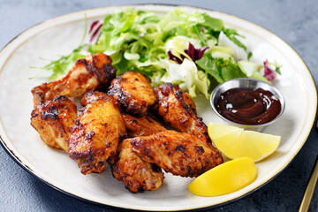 Wall Mural - Air fryer chicken wings with fresh green salad, barbecue sauce and lemon slices.