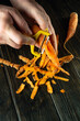 The cook hands peel carrots with a vegetable peeler on the kitchen table in a restaurant. Preparing a vegetable dish for dinner