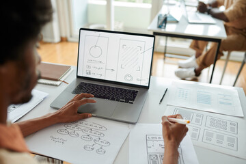 UX designer developing interface for mobile application, view over shoulder