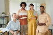 © DragonImages - Portrait of happy diverse startup team standing in office
