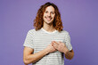 © ViDi Studio - Young grateful smiling man he wearing grey striped t-shirt casual clothes looking camera put folded hands on heart isolated on plain pastel light purple background studio portrait. Lifestyle concept.