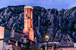 Views of the illuminated Church of Sant Corneli in Collbato, Barcelona at dusk, with the Montserrat mountain in the background