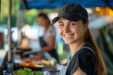 Fototapeta  - Portrait of a young woman at a food market stall, radiating friendliness and community spirit in a local business setting
