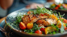 Close Up Of Food Plate With Salmon, Tomatoes, And Leafy Greens On Table