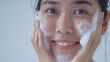A cute asian girl have natural face with clean skin washes with a little foam cleanser and little water on her face in white background