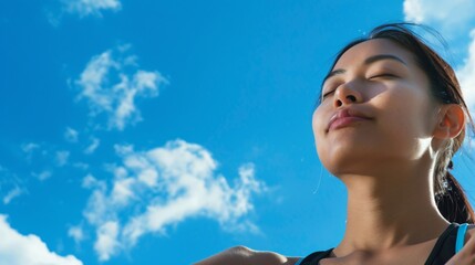 Copyspace beside an Asian woman stretching blue sky above reflecting a journey of fitness and peace