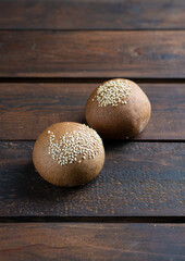 Two wheat buns with sesame seeds on a wooden background