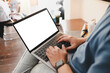 © Thaspol - Mockup image of laptop computer. A man sitting cross legged with laptop computer with blank white screen at coffee cup, over shoulder view