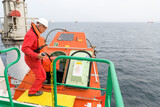 Fototapeta Do pokoju - Seaman wearing lifejacket with vhf radio on Muster station. Abandon ship drill. Free fall boat. Cargo vessel.