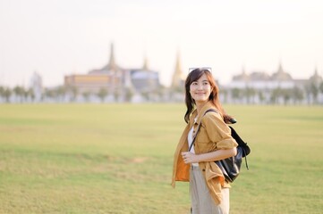 Wall Mural - A Traveler Asian woman in her 30s exploring Wat Pra Kaew. From stunning architecture to friendly locals, she cherishes every moment, capturing it all in her heart and camera for years to come.